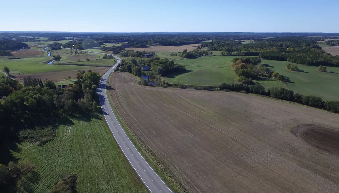 Drönarfoto över E20 vid Vårgårda med vägen som slingrar sig genom åkerlandskap och skogsdungar